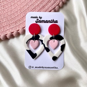 Cut out heart shaped polymer clay cow print earrings with pink and red details and charm Red