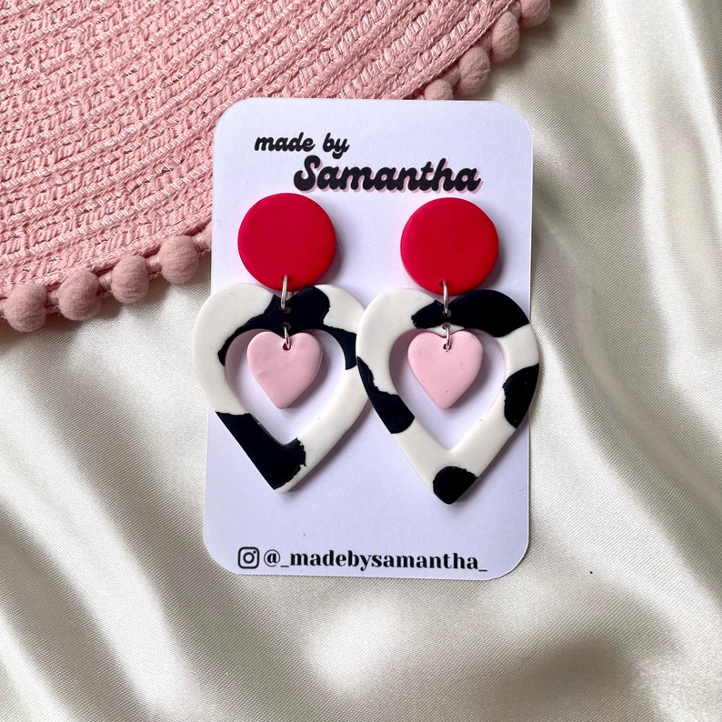 Cut out heart shaped polymer clay cow print earrings with pink and red details and charm Red