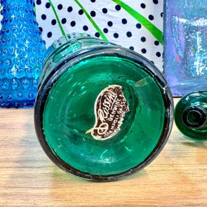 May include: A green glass bottle with a round bottom and a label that reads "Genuine  Polli Glass".
