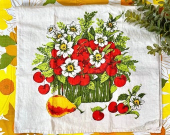 May include: A white tea towel with a vintage floral design featuring a basket overflowing with red cherries and white flowers. A pear is in the bottom right corner of the design.