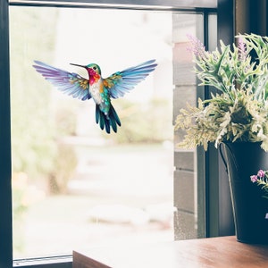 Könnte beinhalten: Ein bunter Kolibri-Fensteraufkleber mit blauen, grünen, violetten und roten Federn. Der Kolibri ist im Flug mit ausgebreiteten Flügeln.