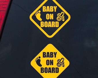 May include: Two yellow diamond-shaped car decals with black text and icons. The text reads "Baby On Board". One icon is a footprint and the other is a pacifier.