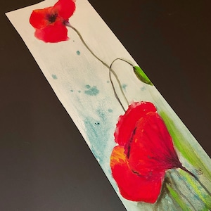 May include: Watercolor painting of two red poppies with green stems and leaves on a white background with blue watercolor splatter.