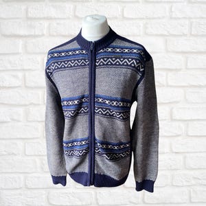 May include: A blue and white patterned zip-up cardigan sweater. The sweater has a geometric design with blue, white, and black accents.