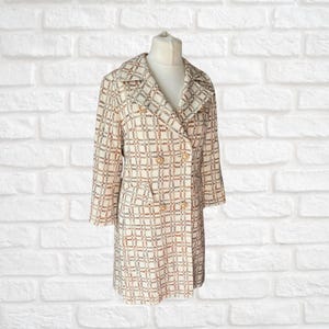 May include: A white double-breasted coat with a checkered pattern in shades of brown, blue and white. The coat has gold buttons and a classic collar.