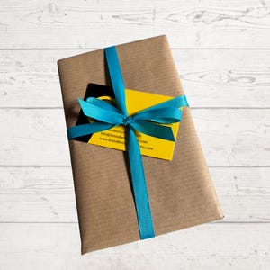 Pode incluir: Um pacote de papel castanho embrulhado com uma fita e um la&ccedil;o azul turquesa. Um cart&atilde;o de visita amarelo com texto preto est&aacute; preso ao pacote. O texto no cart&atilde;o de visita diz "bristalbetty info@bristalbetty.com www.bristalbetty.etsy.com"