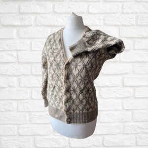 May include: A cream and brown cardigan with a diamond pattern and button closure.