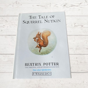 May include: The Tale of Squirrel Nutkin book cover featuring an illustration of a red squirrel holding a nut. The book is by Beatrix Potter and is the original and authorized edition with new color reproductions. The book is published by F. Warne & Co.