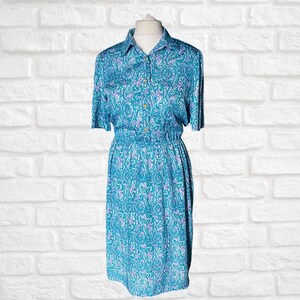 May include: A blue and purple paisley patterned dress with a collared neckline, short sleeves, and a button-up front.