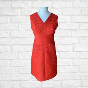 May include: A sleeveless red dress with a V-neckline and a pleated skirt.