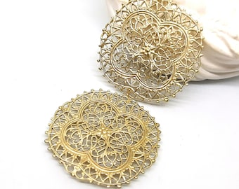 May include: Two gold-colored filigree metal earrings with a circular shape and intricate designs.