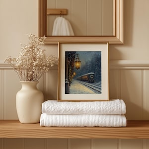 May include: A framed print of a winter train scene with a gold frame sits on a wooden shelf. Below the print are two folded white towels. A white vase with dried flowers is to the left of the print. A mirror hangs above.