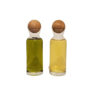 May include: Two glass bottles with wooden stoppers, one filled with green liquid and the other with yellow liquid.