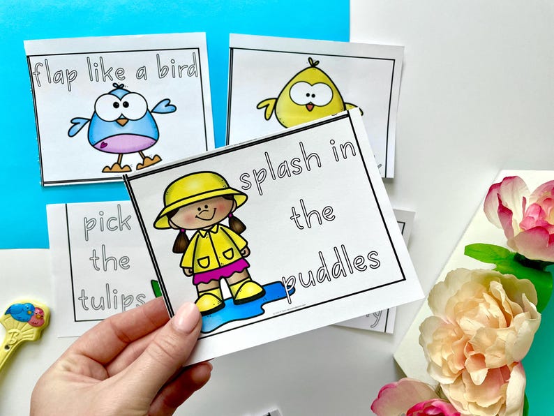 May include: Four printable cards with black outlines and colorful illustrations. The cards feature the phrases "flap like a bird", "pick the tulips", "splash in the puddles", and a chick with a yellow body and black eyes.