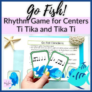 May include: A Go Fish rhythm game set for music centers featuring Ti Tika and Tika Ti notation. The set includes printed instruction sheets and playing cards with blue fish illustrations and musical notes, accompanied by a starfish and coral.