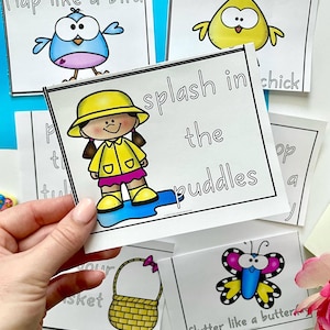 May include: A set of colorful flashcards with illustrations and text. The cards feature a bird, a chick, a girl in a raincoat, a butterfly, and a basket. The text on the cards includes "flap like a bird", "splash in the puddles", "flutter like a butterfly", and "put in your basket".