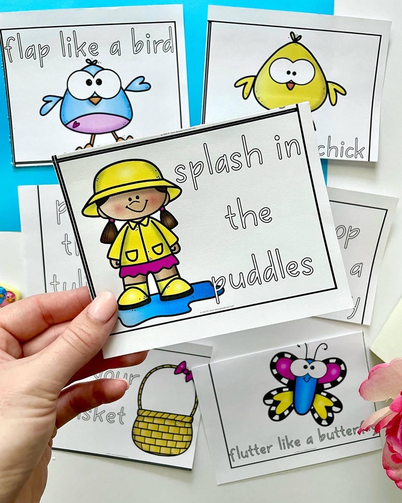 May include: A set of colorful flashcards with illustrations and text. The cards feature a bird, a chick, a girl in a raincoat, a butterfly, and a basket. The text on the cards includes "flap like a bird", "splash in the puddles", "flutter like a butterfly", and "put in your basket".