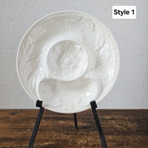 May include: A white ceramic serving dish with a floral and leaf design. The dish has a central well and two side compartments. The dish is on a black metal stand. The text "Style 1" is in the upper right corner.
