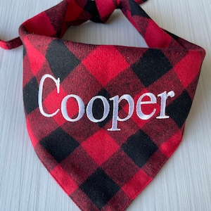 May include: Red and black plaid dog bandana with the name "Cooper" embroidered in white.
