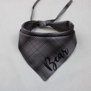 May include: Gray and black plaid dog bandana with the name "Bear" embroidered in black.