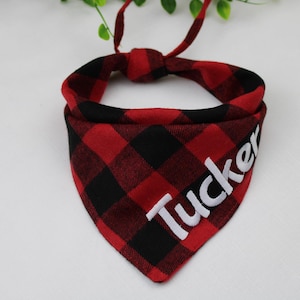 May include: Red and black plaid dog bandana with the name "Tucker" embroidered in white.