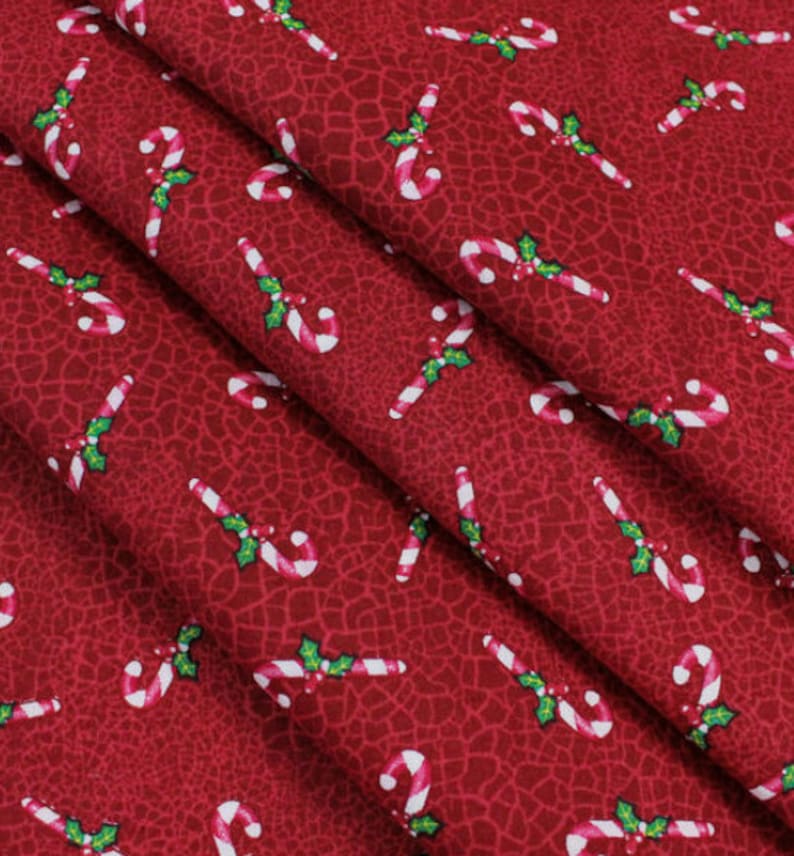 May include: Red fabric with a repeating pattern of white and red candy canes with green holly leaves.