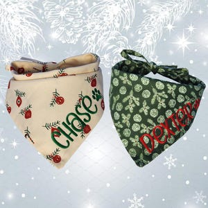 May include: Two Christmas-themed dog bandanas. One is cream-colored with red ornaments and the name "Chase" embroidered in green. The other is dark green with a white pattern and the name "Dexter" embroidered in red.