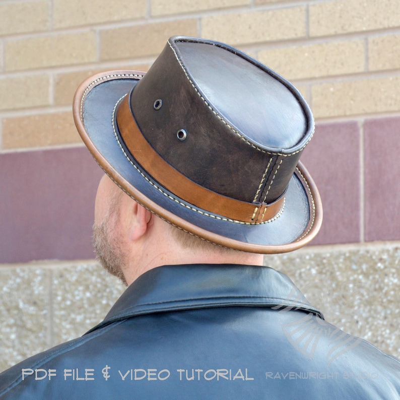 May include: A dark brown leather top hat with a tan leather band and brim. The hat has two small eyelets on the side and is stitched with white thread. The text "PDF FILE & VIDEO TUTORIAL" is visible.