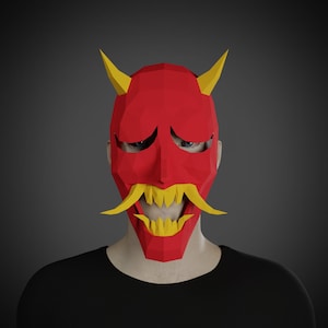 May include: A red and yellow papercraft mask of a demon with a wide, toothy grin. The mask has horns and a mustache.