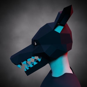 Puede incluir: Una máscara de lobo de origami negra con dientes afilados y un brillo azul. La máscara la lleva una persona con una camisa negra.
