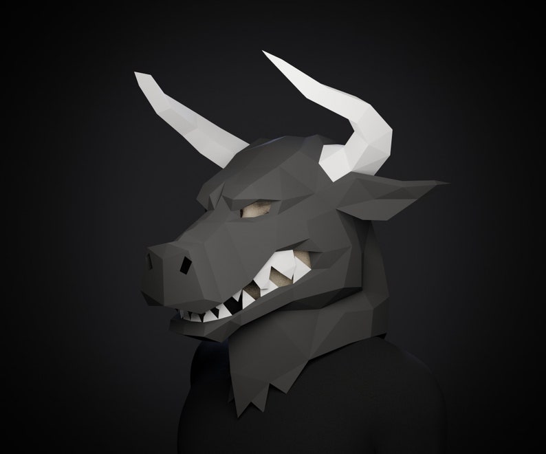 May include: A black papercraft bull mask with white horns. The mask has a fierce expression with sharp teeth and a detailed face.