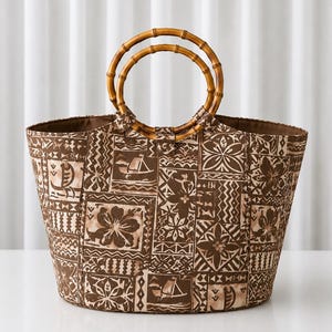 May include: A brown and tan tote bag featuring a patchwork pattern of floral motifs and sailing ships. The bag has two circular bamboo handles attached to the top. The fabric displays a repeating print of various geometric and botanical designs.
