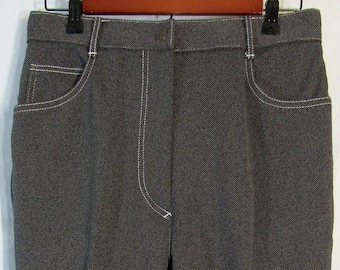 May include: Dark gray trousers with white stitching details. The pants have a straight leg cut and feature front pockets. The stitching is visible along the seams and pocket edges. The trousers are hanging on a wooden hanger.