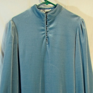 May include: A light blue velvet dress with a high neck and long sleeves. The dress has a button closure at the neck and a small tag on the sleeve.