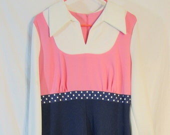 May include: A vintage-style dress featuring a white collar and long sleeves. The bodice is pink, and the waist is accented with a navy blue band with white polka dots. The skirt is navy blue, creating a color-blocked design.