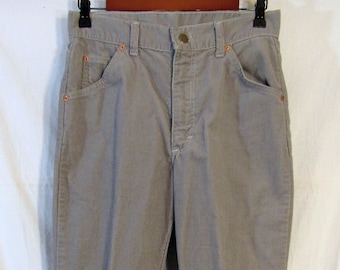 May include: A pair of light gray corduroy pants. The pants have a classic five-pocket design with a button and zipper closure. The stitching and rivets are a contrasting orange color. The pants are hanging on a black hanger.