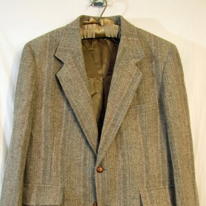 May include: A brown tweed blazer with a herringbone pattern. The blazer has two button closures and two flap pockets.