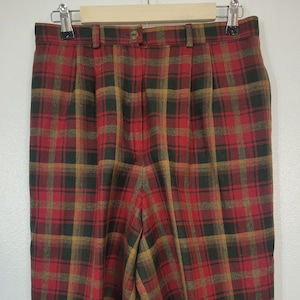May include: Red, black, and gold plaid shorts with a button closure and belt loops. The shorts are hanging on a metal hanger against a white background. The fabric has a textured appearance.