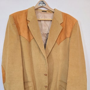May include: A tan corduroy blazer with brown suede elbow patches and shoulder accents. The blazer has a single-breasted closure with four buttons and two front pockets.