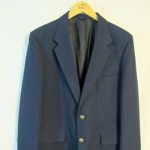 May include: A dark blue blazer with gold buttons. The blazer has a single breasted closure and two flap pockets.