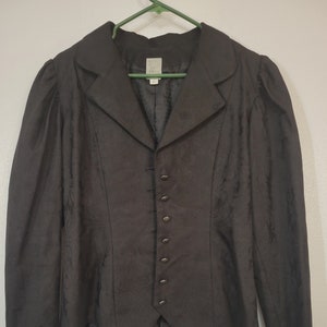 May include: A black blazer with a fitted waist and a pointed hem. The blazer has a collar and a button-up front.