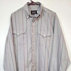 May include: A gray button-down shirt with vertical stripes in black and burgundy. The long-sleeved shirt has two chest pockets and a button-down collar. The brand name "Alexander & Son" is visible on the label.