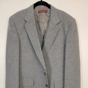 May include: A gray Levi's Menswear blazer with a two-button closure, two front pockets, and a notched lapel. The blazer is hanging on a black hanger against a white background. The label "Levi's Menswear" is visible.