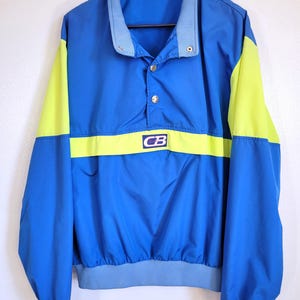 May include: A blue and yellow vintage jacket with a stand-up collar and snap closure. The jacket features a blue body with yellow sleeves and a yellow band across the chest. The letters "CB" are visible on the chest.