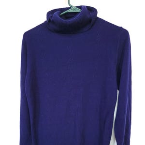 May include: A purple turtleneck sweater with a textured pattern.
