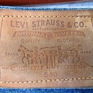 May include: A brown leather Levi Strauss & Co. clothing label with the text "Original Quality Clothing" and a design of two horses pulling a wagon. The label has the text "Trade Mark" and "San Francisco, Cal."