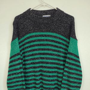 May include: A black and green striped sweater with silver glitter throughout. The sweater has a crew neck and long sleeves.