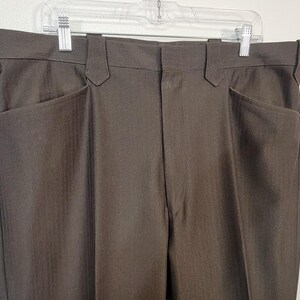 May include: A pair of brown dress trousers with a subtle pinstripe pattern. The trousers have two front pockets and two back pockets.