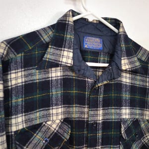 Pu&ograve; includere: Una camicia a maniche lunghe con bottoni caratterizzata da un motivo a quadri blu navy scuro, verde bosco e crema. La camicia presenta una fodera interna del colletto trapuntata blu navy e un'etichetta blu Pendleton cucita all'interno.