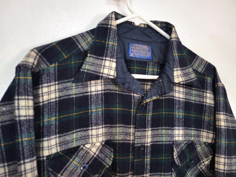 Pu&ograve; includere: Una camicia a maniche lunghe con bottoni caratterizzata da un motivo a quadri blu navy scuro, verde bosco e crema. La camicia presenta una fodera interna del colletto trapuntata blu navy e un'etichetta blu Pendleton cucita all'interno.